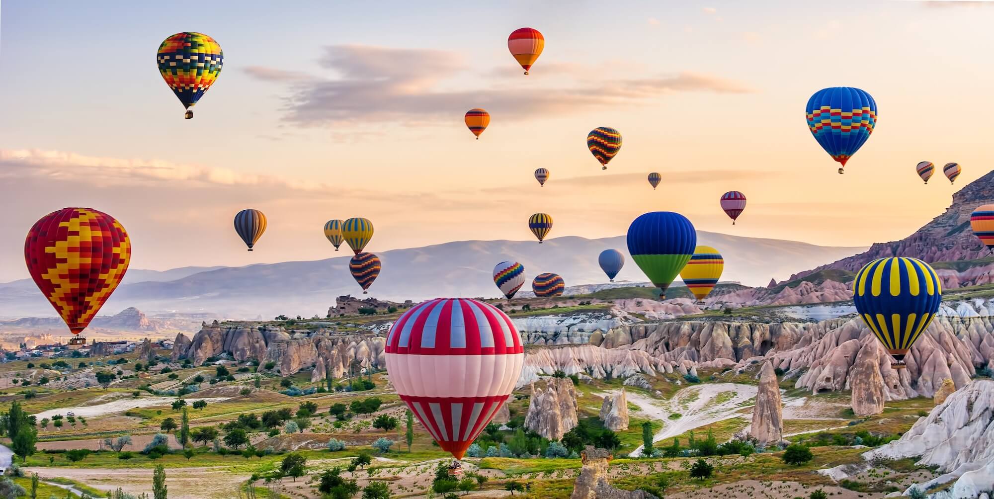 Vibrant hot air balloons rising over a scenic landscape at sunrise, symbolising Supr Bueno’s web design pricing plans that help elevate your online presence.